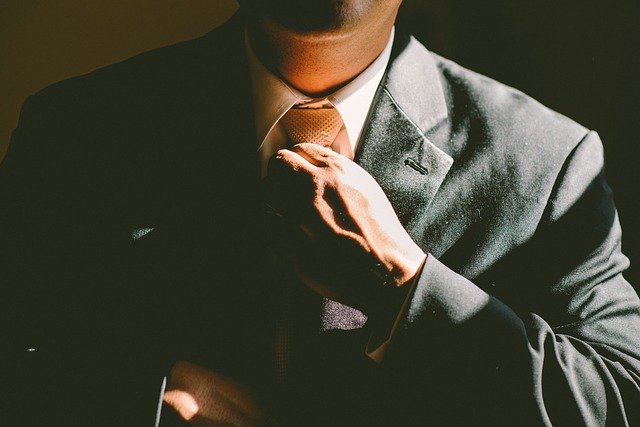 Muž v obleku upravující si kravatu